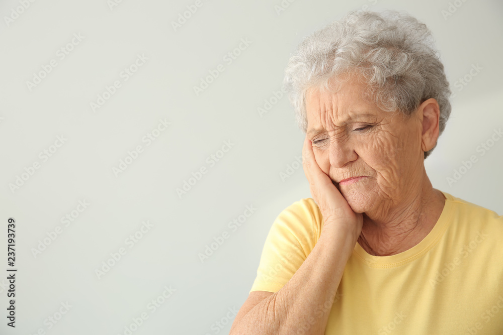 Senior woman suffering from toothache on light background Senior woman suffering from toothache on light background