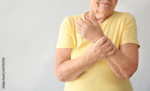 Senior woman suffering from pain in wrist on light background photo