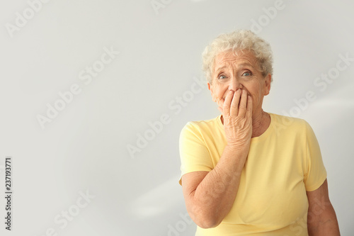 Portrait of elderly woman after making mistake on light background