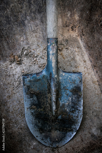 Dirty shovel soiled in the soil and clay. Old work tool, deep hole. 