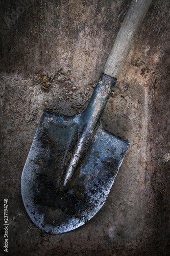Dirty shovel soiled in the soil and clay. Old work tool, deep hole. 