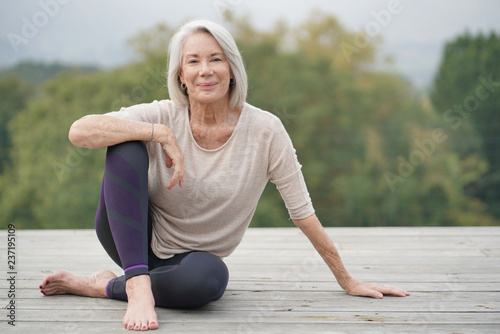   Beautiful elderly woman sitting outdoors in sportswear photo