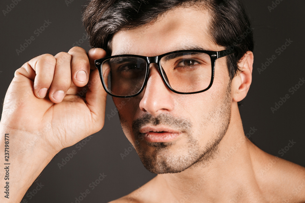 Young man isolated over dark background wearing eyeglasses. Young man isolated over dark background wearing eyeglasses.