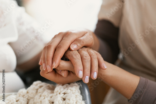 Closeup of hands of a young woman holding hand of an senior lady photo