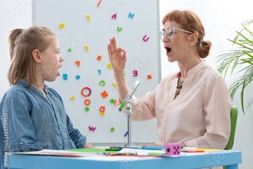 Speech therapist teaching vowels to a girl photo