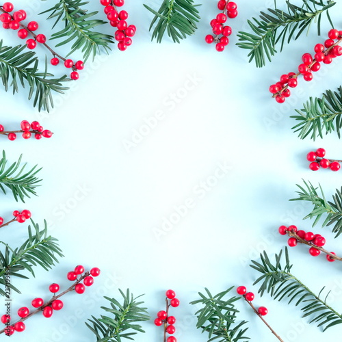 Christmas modern composition. Wreath made of green fir tree branches and red berries on pastel blue background. Christmas, New Year, winter concept. Flat lay, top view, copy space