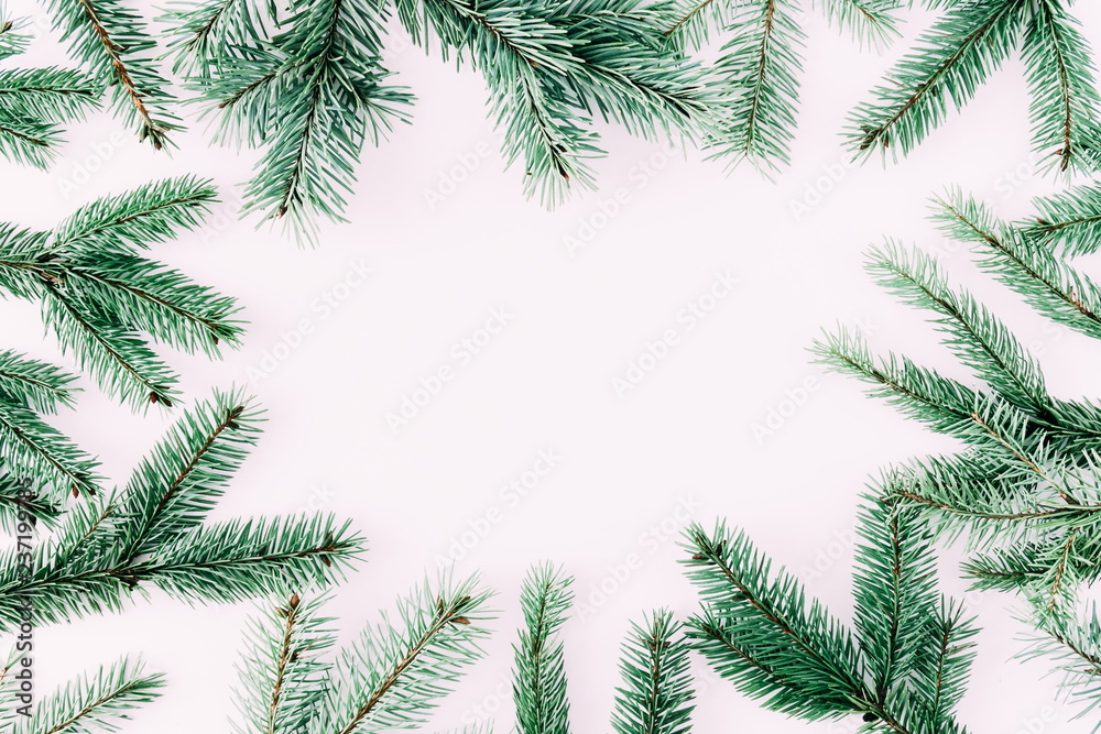 Christmas modern composition. Frame made of green fir tree branches on pastel pink background. Christmas, New Year, winter concept. Flat lay, top view, copy space