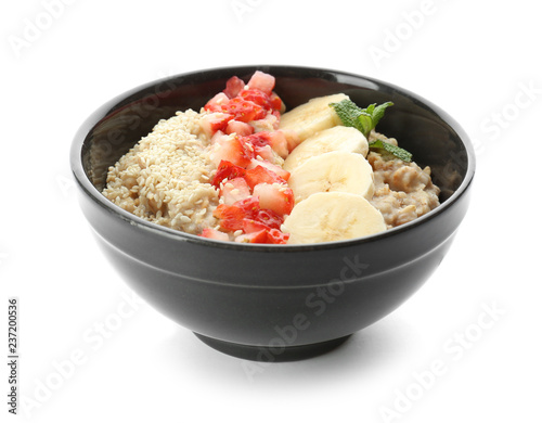 Bowl with tasty oatmeal, sliced banana and strawberry on white background