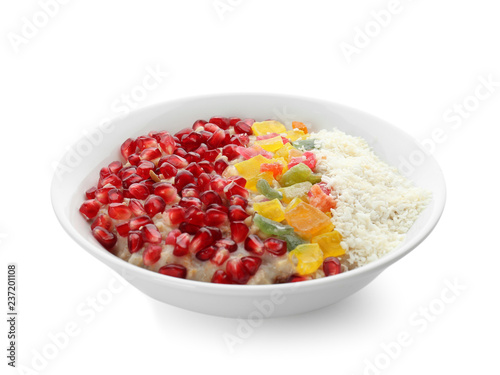 Plate with tasty oatmeal, pomegranate seeds and succades on white background