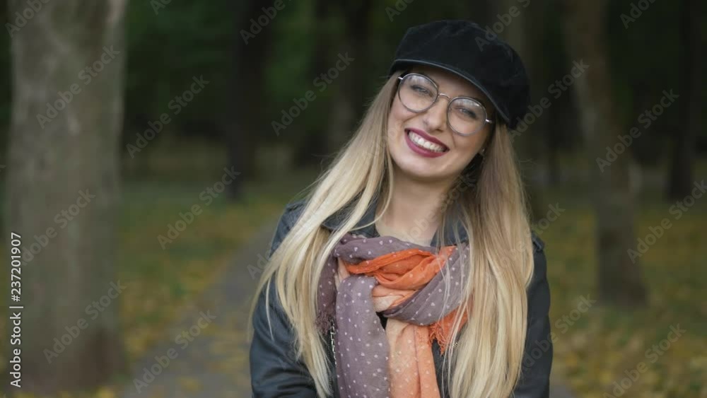 Young adorable blonde woman having fun at city park cold season, smiling into the camera. Close up, shallow depth of field. Young adorable blonde woman having fun at city park cold season, smiling into the camera. Close up, shallow depth of field.