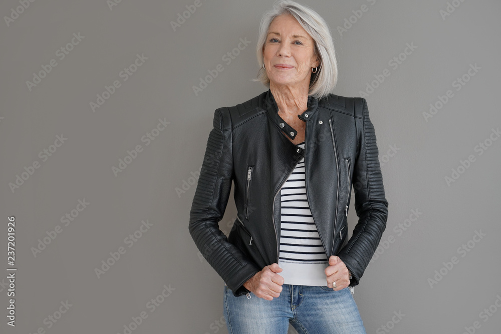  Modern senior woman in leather jacket on isolated grey background - obrazy, fototapety, plakaty 