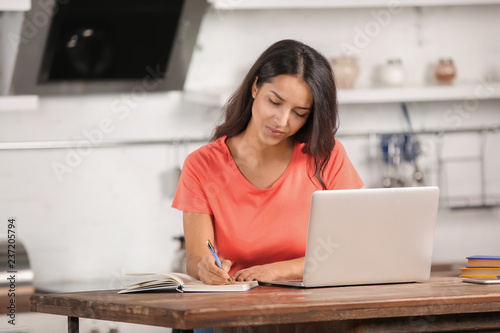 Young woman working with laptop in kitchen photo