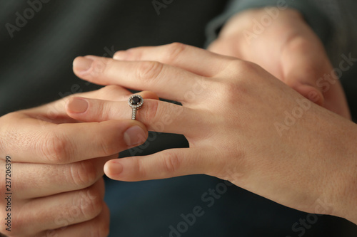 Young man putting engagement ring on fiancee's finger, closeup