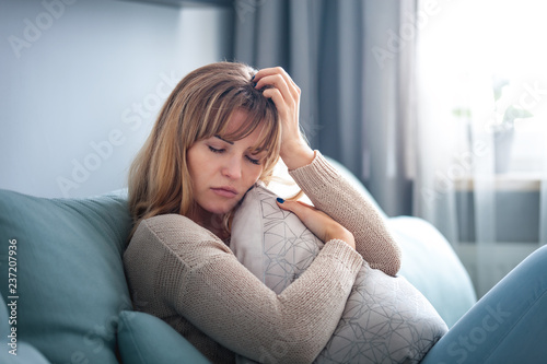 Depressed woman sitting on sofa at home  thinking about important things