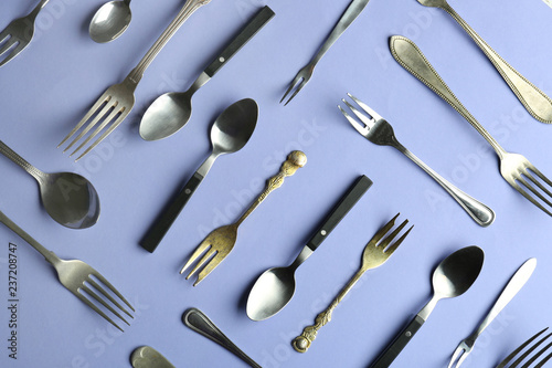 Spoons and forks on color background