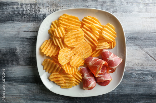 Tasty crispy potato chips with bacon on plate photo