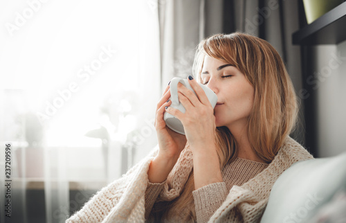 Fotografía Happy woman in soft sweater relaxing at home with cup of hot tea or coffee