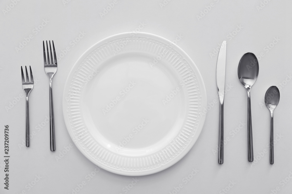 Plate and set of cutlery on white background, flat lay