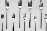 Many forks on white textured  background, flat lay