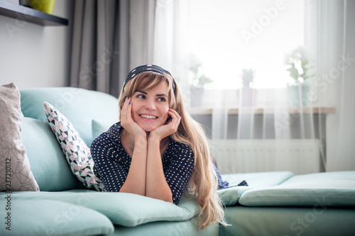 Happy woman lying on couch and thinking about something at home, casual style indoor shoot © leszekglasner