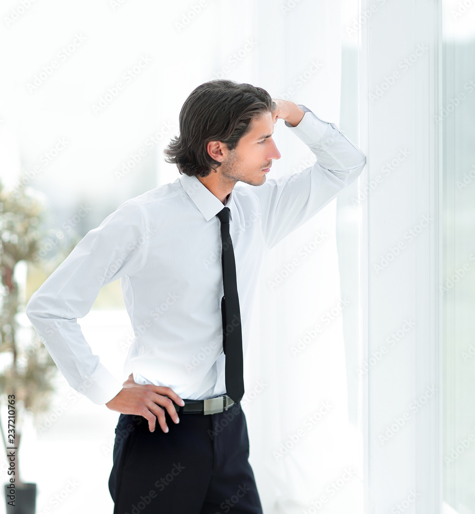 serious young businessman on background of office serious young businessman on background of office