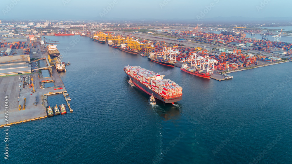 Aerial view Tug boats drag container ship to sea port and working crane bridge loading container for import  export, shipping or transportation concept background.