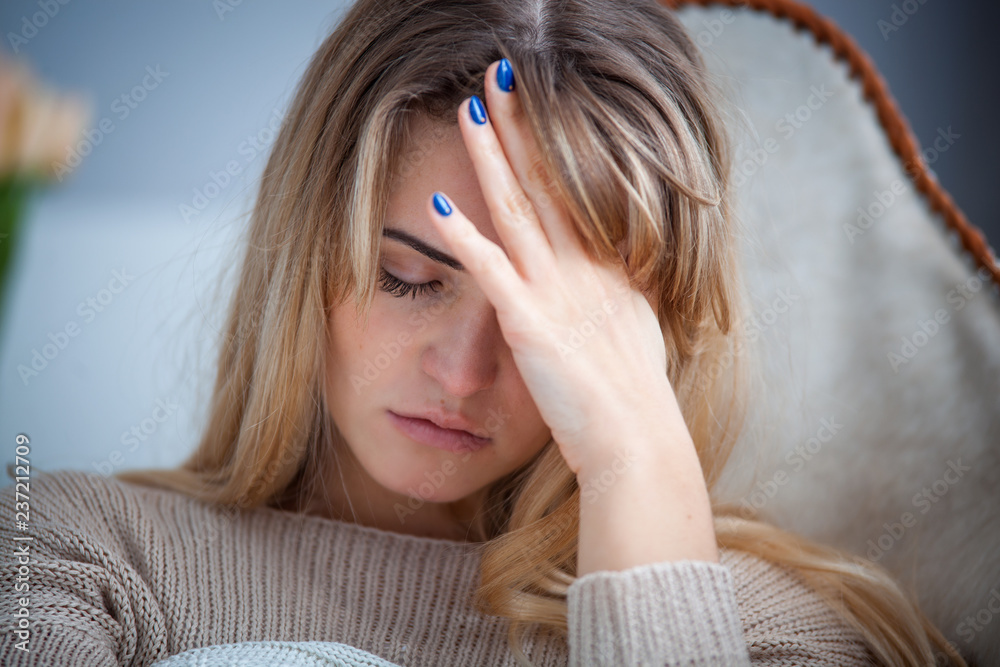 Naklejka premium Sad woman sitting on armchair at home thinking about something, negative emotions