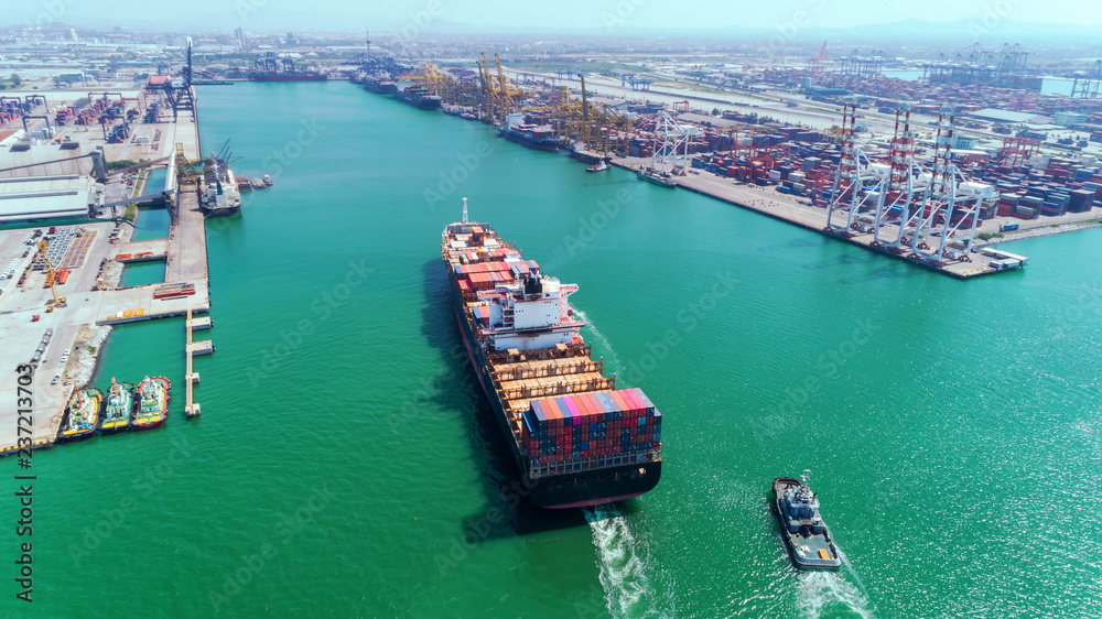 Aerial view Tug boats drag container ship to sea port and working crane bridge loading container for import  export, shipping or transportation concept background.