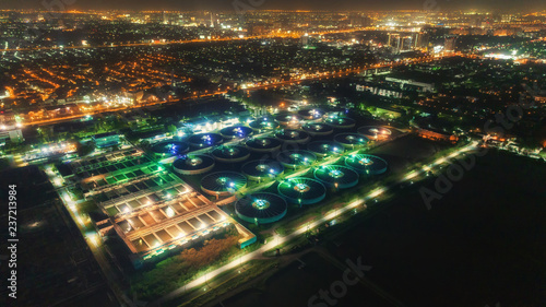 Aerial view water treatment plant at night with cityscape for environment concept.