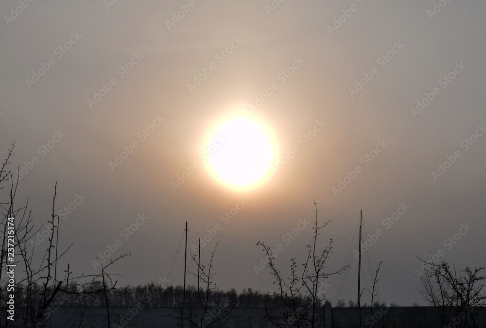 Bright sun in the dark sky. Winter frosty day. Sunset in the North.