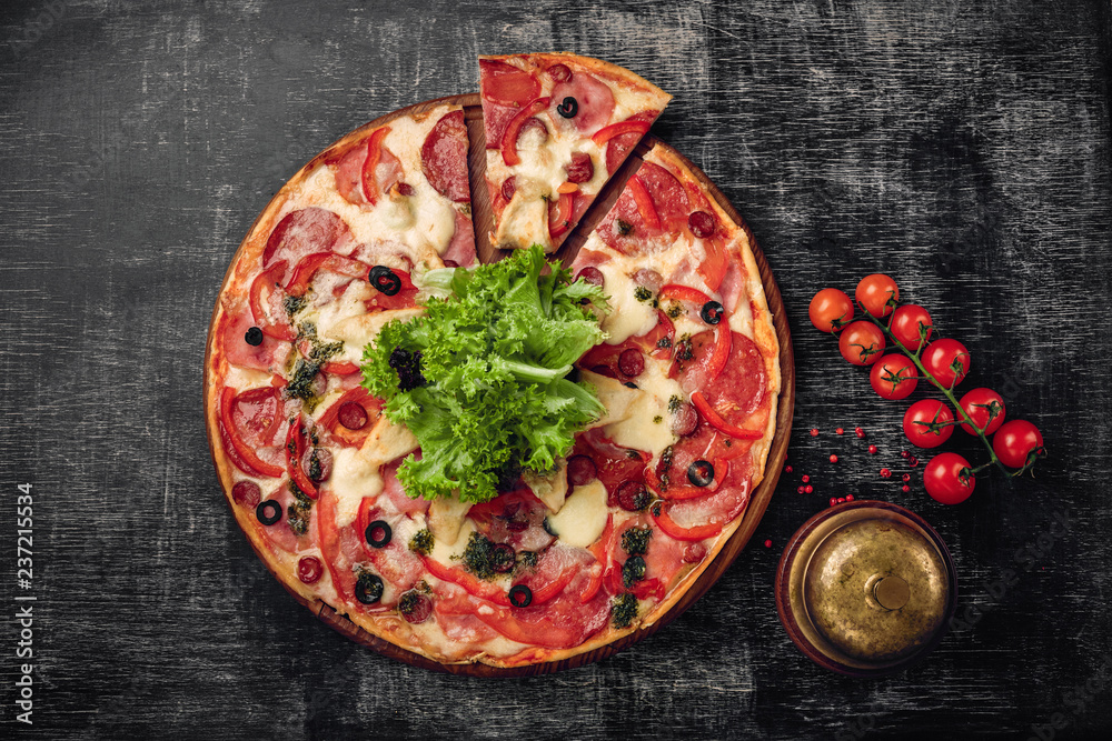 Pizza with ham, salami, cheese, mushrooms, cherry tomatoes, bell