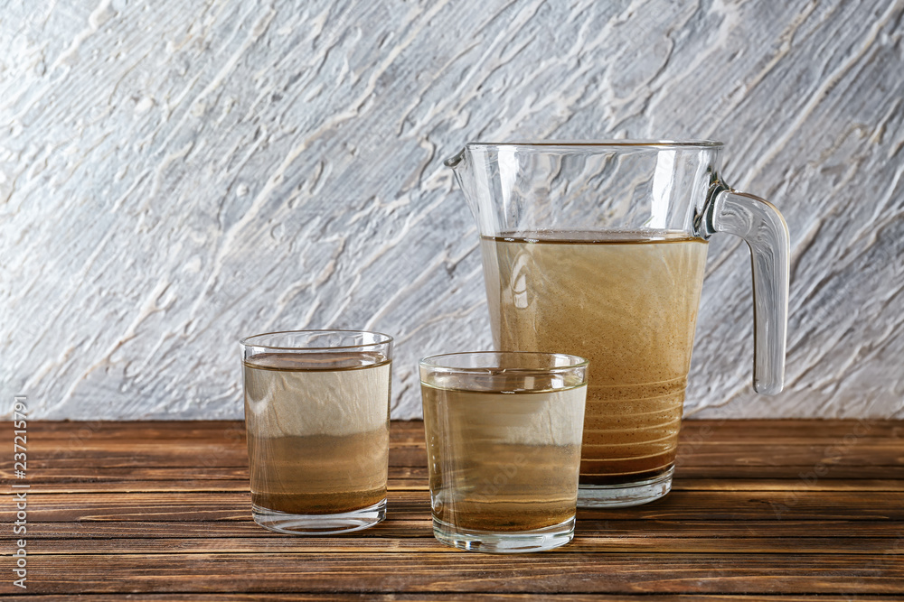 Jug and glasses with dirty water on wooden table Jug and glasses with dirty water on wooden table