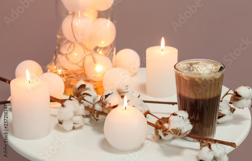 Cotton flowers  burning candles and glass of drink on table