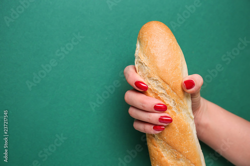 Fotobehang Woman holding fresh baguette on color background. Erotic concept