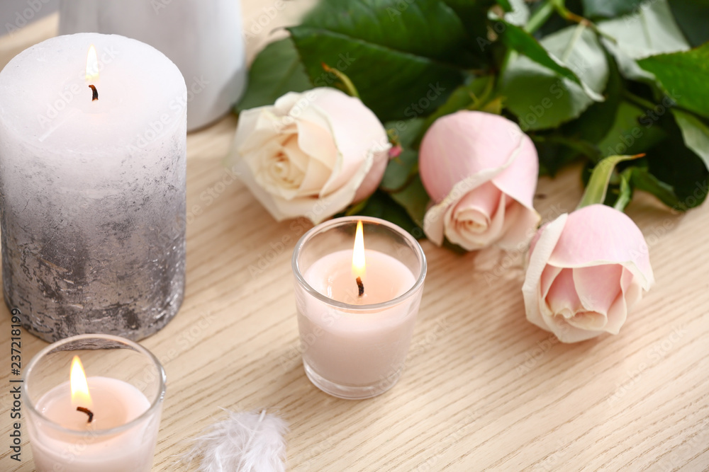 Burning candles and beautiful flowers on wooden table