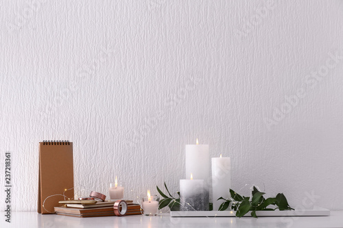 Beautiful composition with burning candles on table near white wall