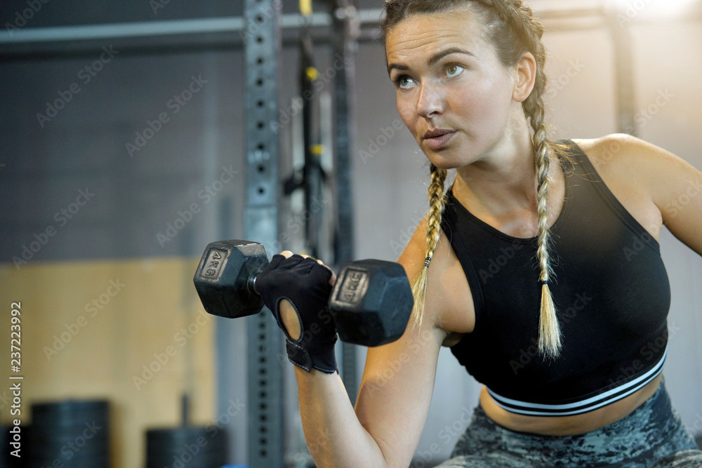 Fototapeta premium Woman in a gym lifting weights