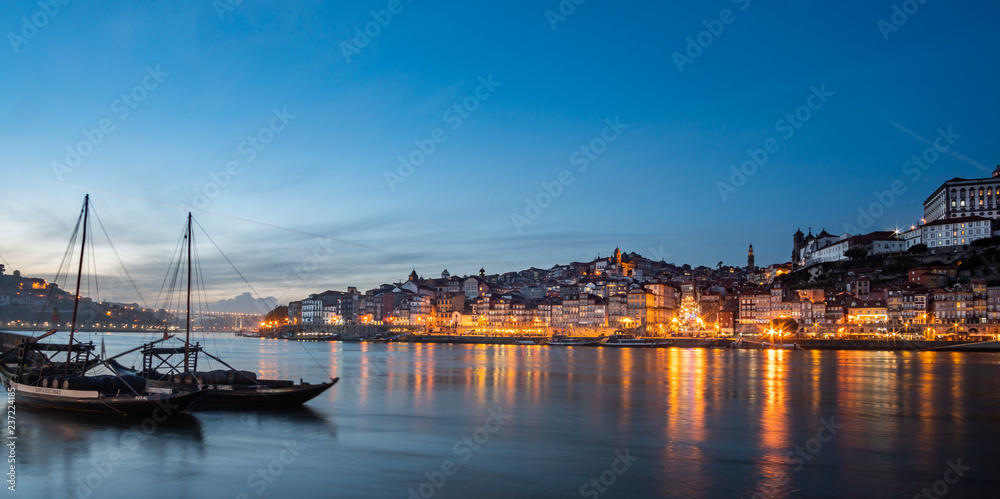 view of the city of poto at night with classic rabelo boat on the river