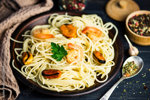 spaghetti with seafood in a plate and spices on a wooden board