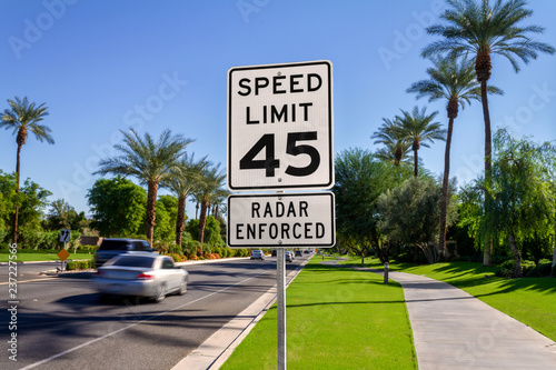 Speed Limit 45 Radar Enforced road sign with passing cars on a California street.