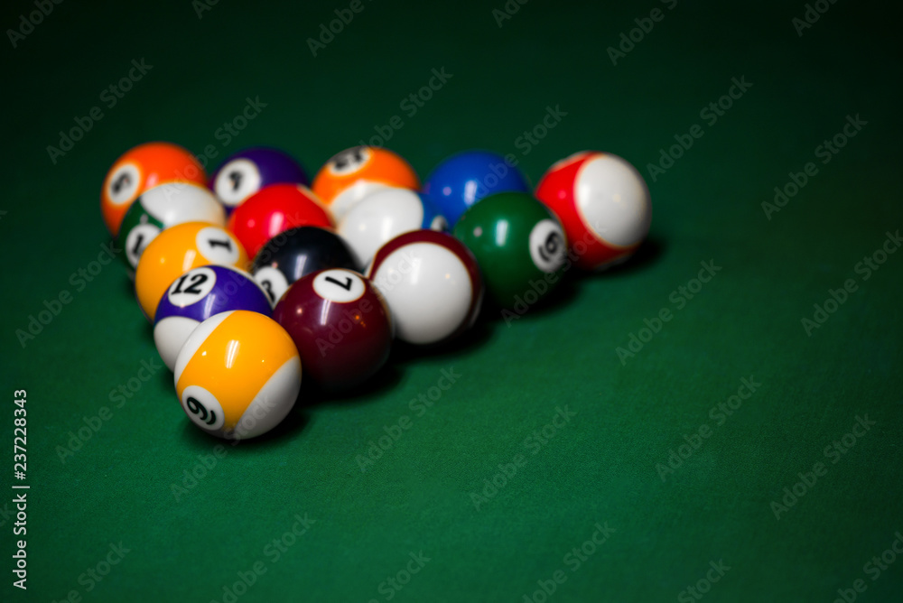 Sport billiard balls set arranged in shape of triangle on green billiard table in pub. Players are ready for the first hit of the round to start the billiard game. Sport billiard balls set arranged in shape of triangle on green billiard table in pub. Players are ready for the first hit of the round to start the billiard game.