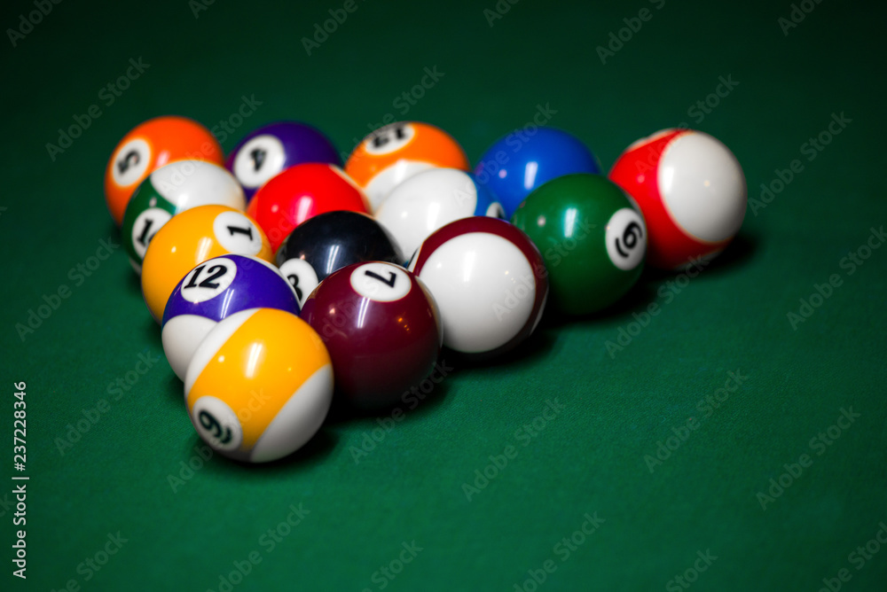 Sport billiard balls set arranged in shape of triangle on green billiard table in pub. Players are ready for the first hit of the round to start the billiard game. Sport billiard balls set arranged in shape of triangle on green billiard table in pub. Players are ready for the first hit of the round to start the billiard game.