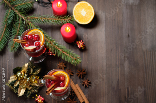 Mulled wine on a wooden background with candles, pine branches and Christmas lights. Selective focus. Copy space