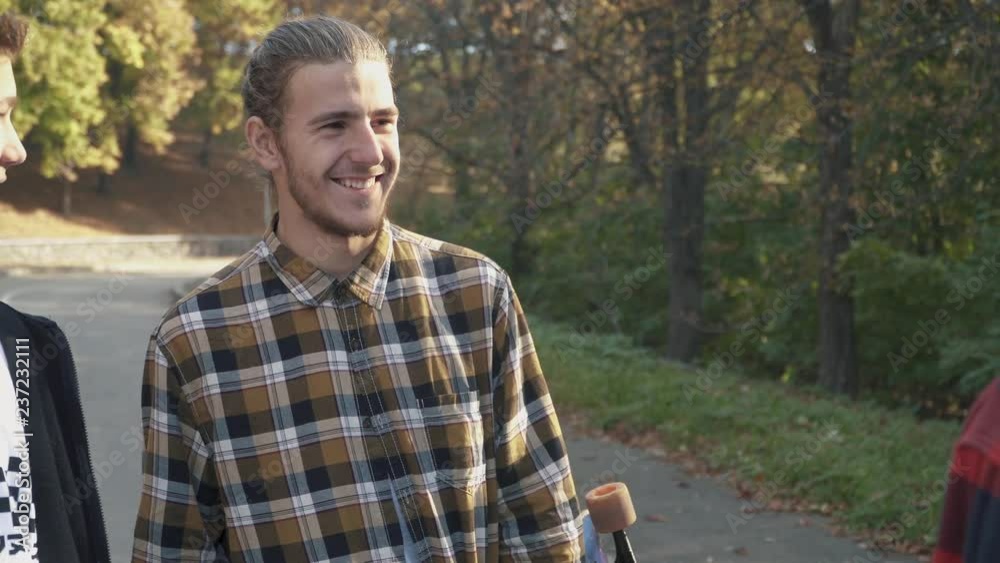 A company of young people smiling communicates. Guy in a plaid shirt with a skate in his hands. Hobbies and lifestyle A company of young people smiling communicates. Guy in a plaid shirt with a skate in his hands. Hobbies and lifestyle