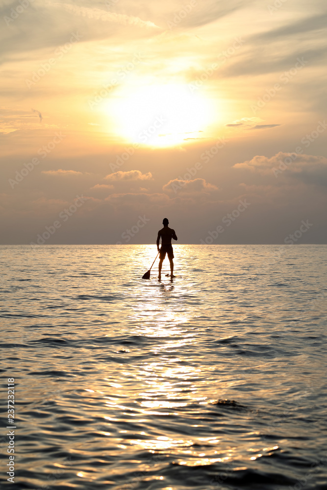 Sunset Silhouette Of Young Handsome Man Paddling On Surfboard Toward The Horizon In The Open Sea Beautiful Scenic Sunset