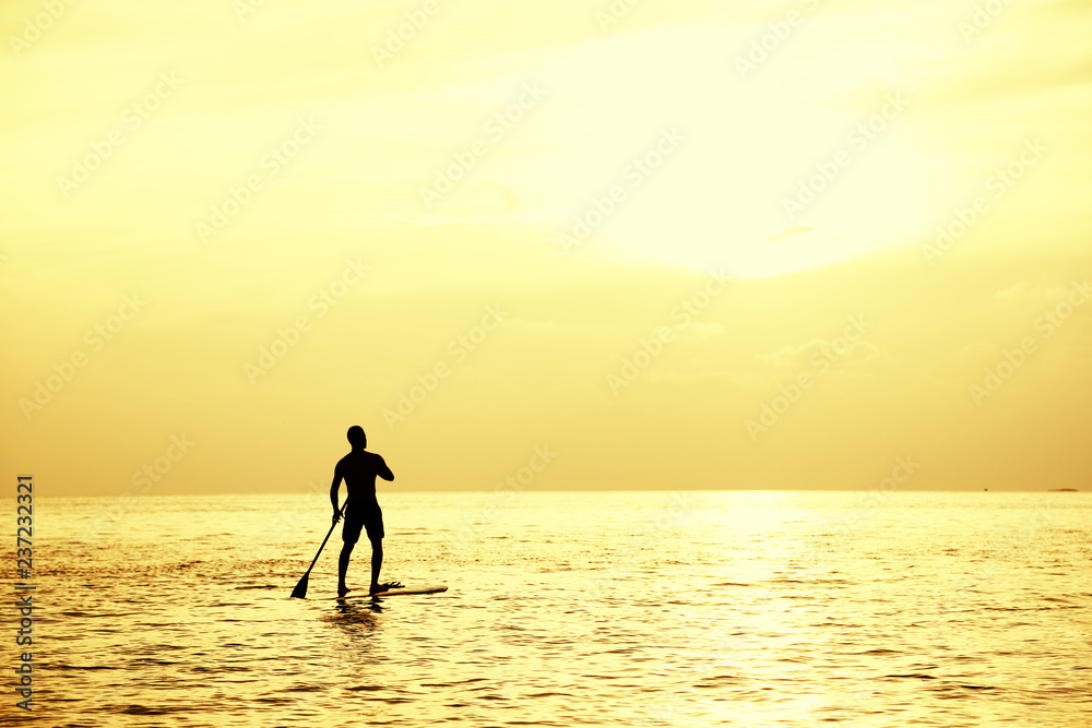 Sunset Silhouette Of Young Handsome Man Paddling On Surfboard Toward The Horizon In The Open Sea Beautiful Scenic Sunset