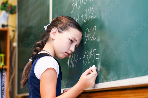 child standing near the blackboard in school with a sad face. Adolescent learning difficulties