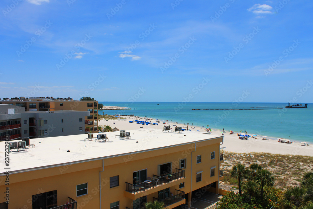 Madeira Beach, Florida, USA. View of beach as seen from a distance and above, looking across the rooftops of condominium buildings. Dredging ship in gulf.