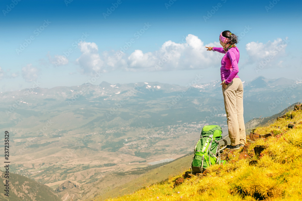 happy woman backpacker and hiker looking at the view with arms outstretched on mountain top