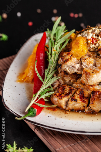 The concept of Mexican cuisine. Grilled pork steak with spicy sauce, red pepper salsa, peaches and shrimps. Beautiful serving in the restaurant. Background image